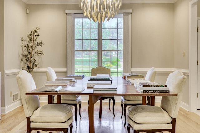 dining room featuring a notable chandelier, light hardwood / wood-style floors, and ornamental molding