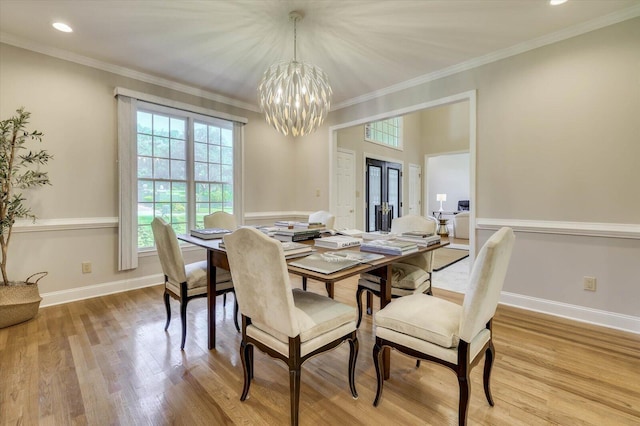 dining area featuring a chandelier, french doors, light hardwood / wood-style floors, and crown molding