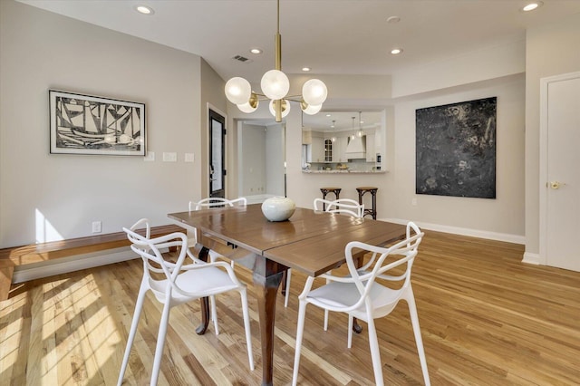 dining space featuring light hardwood / wood-style floors and a notable chandelier