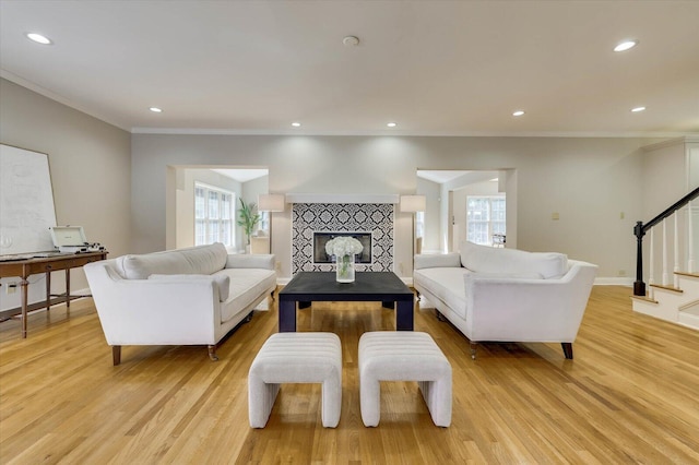 living room with a fireplace, a healthy amount of sunlight, light hardwood / wood-style flooring, and crown molding