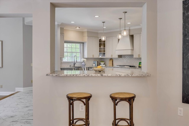 kitchen featuring light stone countertops, sink, tasteful backsplash, and custom exhaust hood