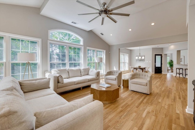 living room featuring vaulted ceiling, light hardwood / wood-style floors, and ceiling fan with notable chandelier