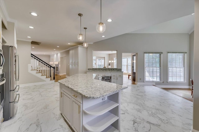 kitchen with light stone countertops, stainless steel fridge, pendant lighting, a center island, and white cabinetry