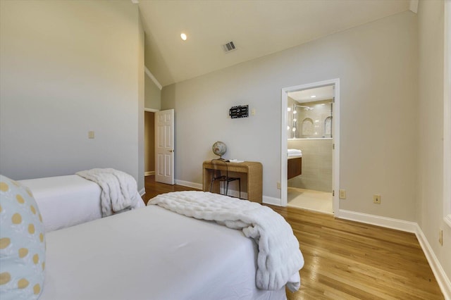 bedroom with wood-type flooring, connected bathroom, and lofted ceiling