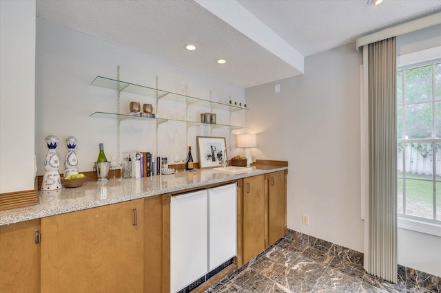 bar featuring light stone counters, a healthy amount of sunlight, and a textured ceiling