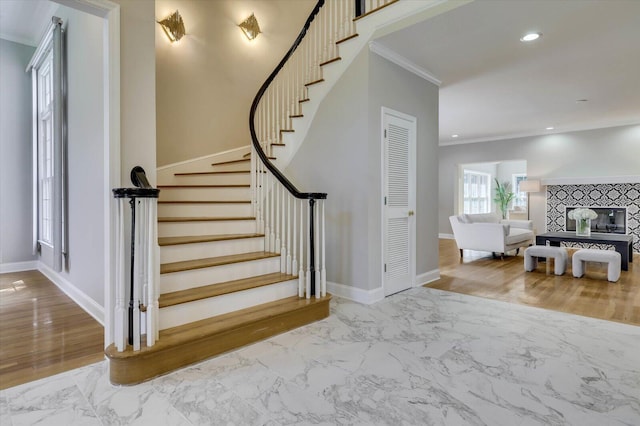 stairway featuring crown molding and a tile fireplace