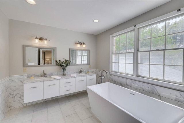 bathroom with tile patterned floors, a washtub, vanity, and tile walls