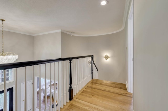 staircase featuring wood-type flooring, a chandelier, and ornamental molding