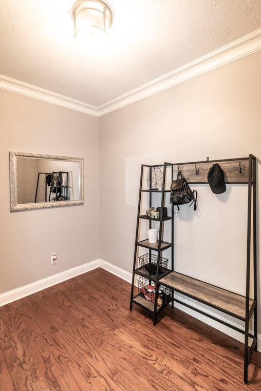 interior space with crown molding, baseboards, and wood finished floors