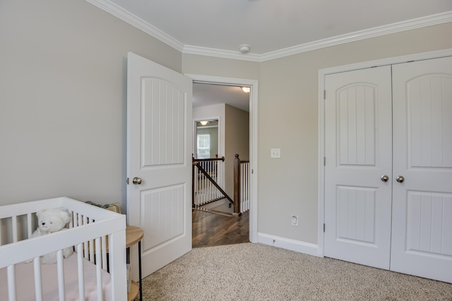 unfurnished bedroom with crown molding, carpet floors, a closet, and a crib