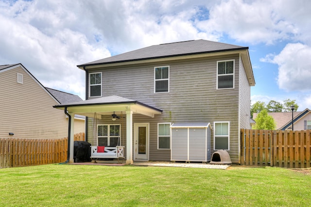 rear view of house featuring ceiling fan and a yard