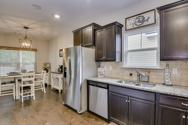 kitchen with sink, appliances with stainless steel finishes, hanging light fixtures, dark brown cabinets, and dark hardwood / wood-style flooring