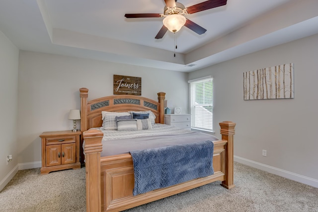 carpeted bedroom featuring ceiling fan and a raised ceiling