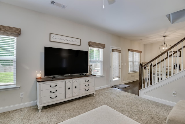 carpeted living room featuring a notable chandelier