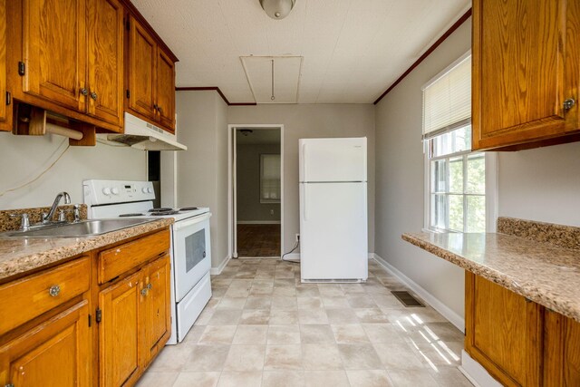 kitchen featuring white appliances, light stone counters, and sink