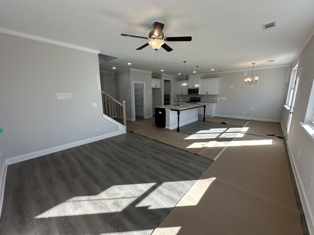 unfurnished living room with crown molding, ceiling fan with notable chandelier, dark hardwood / wood-style floors, and sink