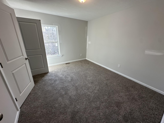 unfurnished room featuring dark colored carpet