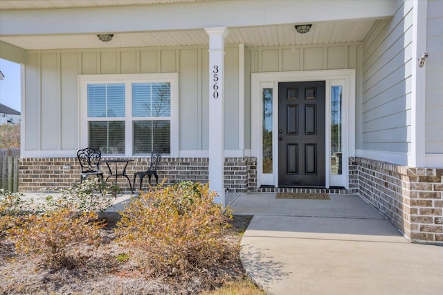 property entrance featuring covered porch, brick siding, and board and batten siding