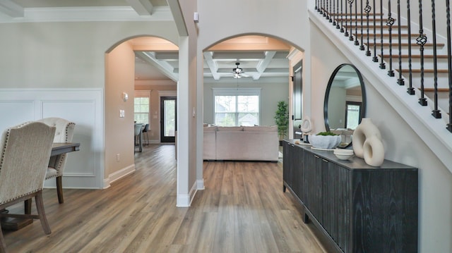 entryway with ceiling fan, arched walkways, light wood-type flooring, ornamental molding, and coffered ceiling