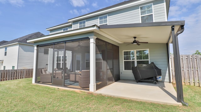 rear view of house with ceiling fan, fence, a sunroom, a patio area, and a lawn