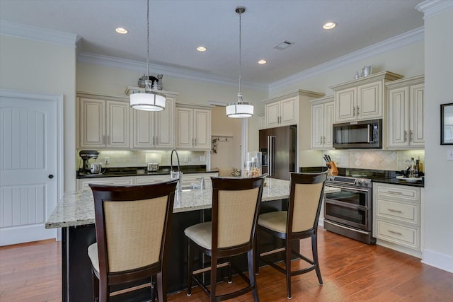 kitchen with visible vents, dark wood-type flooring, an island with sink, a sink, and appliances with stainless steel finishes