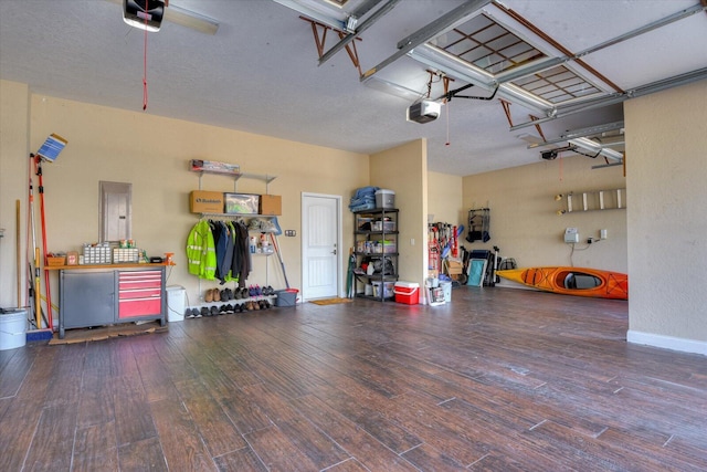 garage featuring electric panel, a garage door opener, and baseboards