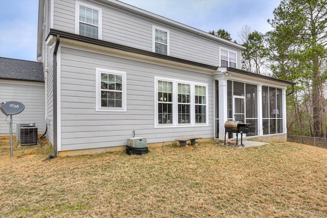 back of property with fence, central AC unit, a lawn, and a sunroom