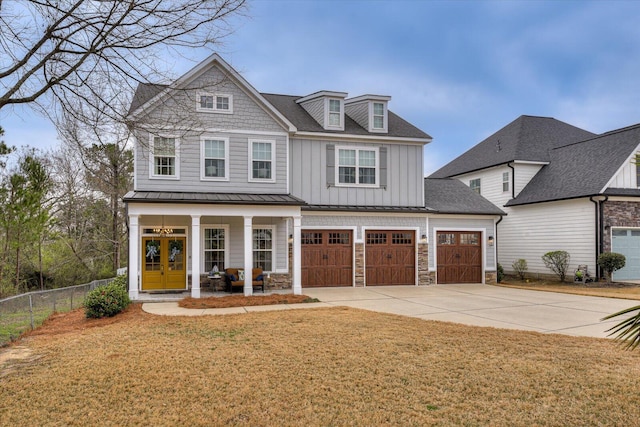 shingle-style home with a front yard, fence, concrete driveway, french doors, and board and batten siding