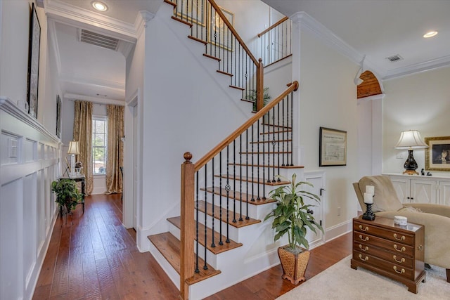 stairway featuring visible vents, baseboards, ornamental molding, and hardwood / wood-style flooring