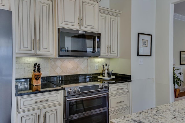 kitchen with backsplash, stainless steel appliances, and cream cabinets