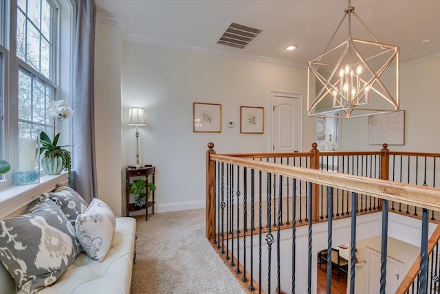 hallway with visible vents, crown molding, baseboards, a chandelier, and carpet flooring