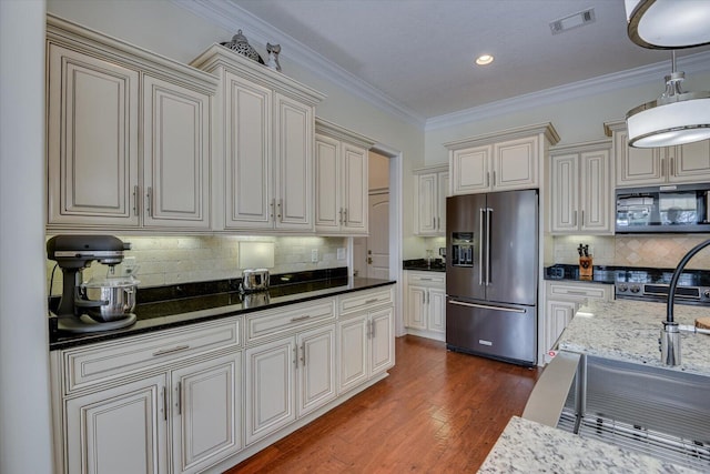 kitchen featuring visible vents, dark wood-style flooring, ornamental molding, black microwave, and high end refrigerator