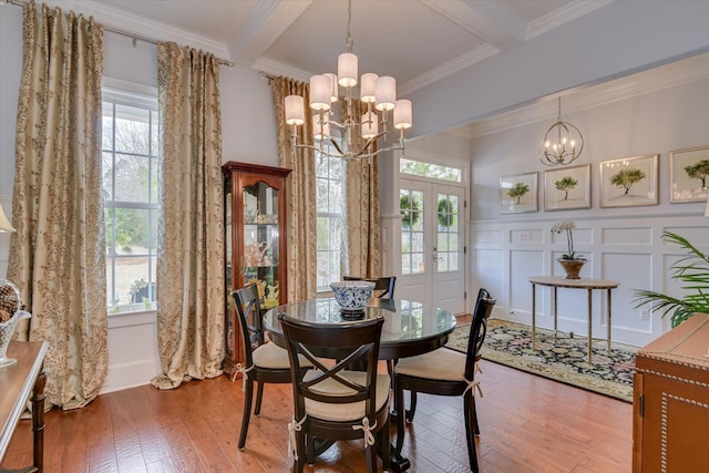 dining space featuring a chandelier, a decorative wall, french doors, and hardwood / wood-style floors