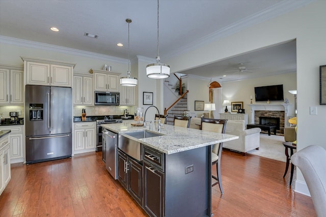 kitchen featuring visible vents, a breakfast bar, appliances with stainless steel finishes, a fireplace, and a sink