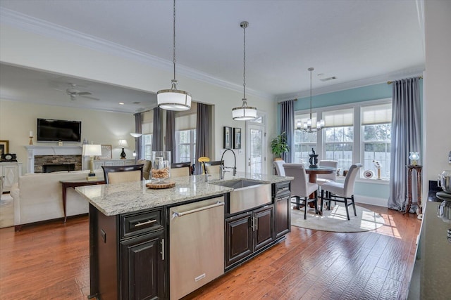 kitchen with dishwasher, dark wood-type flooring, a stone fireplace, and a sink