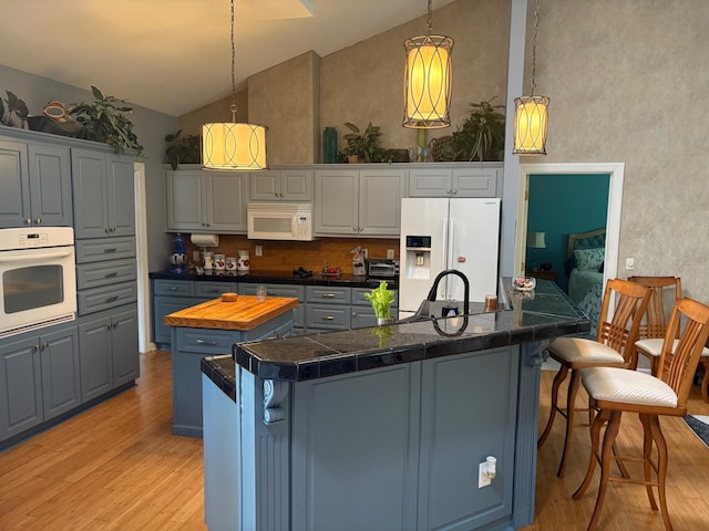 405 Sawgrass Cv, Mccormick, SC 29835 - kitchen featuring white appliances, an island with sink, light wood-style floors, a kitchen breakfast bar, and high vaulted ceiling