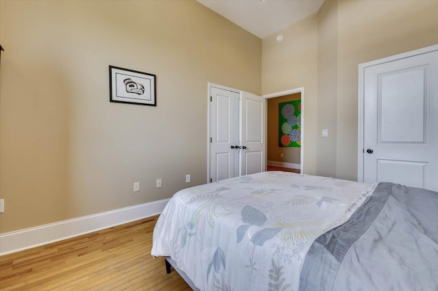 bedroom with light wood-type flooring and vaulted ceiling