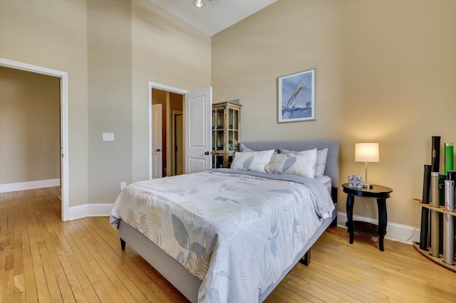 bedroom featuring a high ceiling and light wood-type flooring