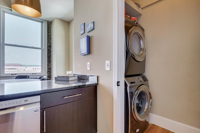 laundry room with stacked washer and dryer and light hardwood / wood-style flooring