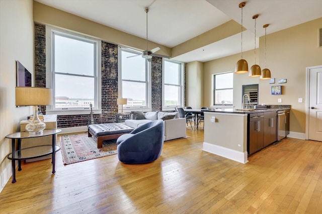 living room featuring light wood-type flooring, ceiling fan, and sink