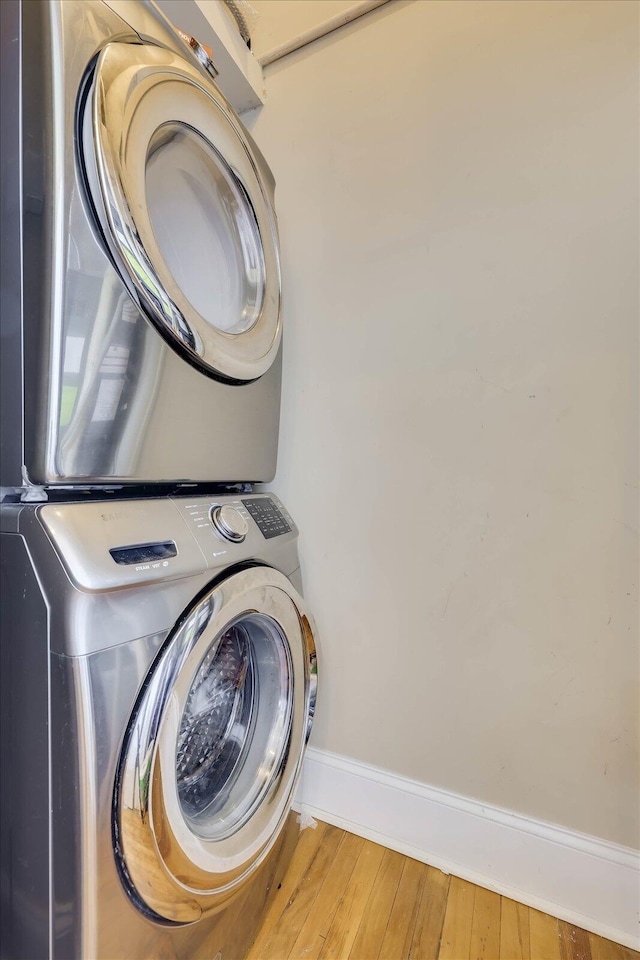 laundry area featuring stacked washer and dryer and hardwood / wood-style flooring