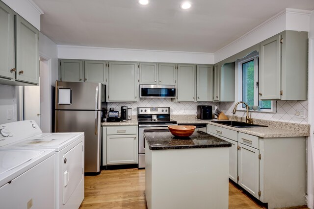 kitchen with appliances with stainless steel finishes, a sink, washer and dryer, backsplash, and ornamental molding