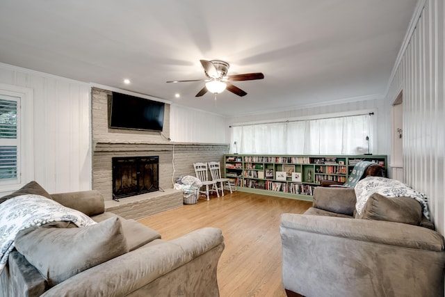 living area featuring a ceiling fan, a fireplace, wood finished floors, crown molding, and recessed lighting