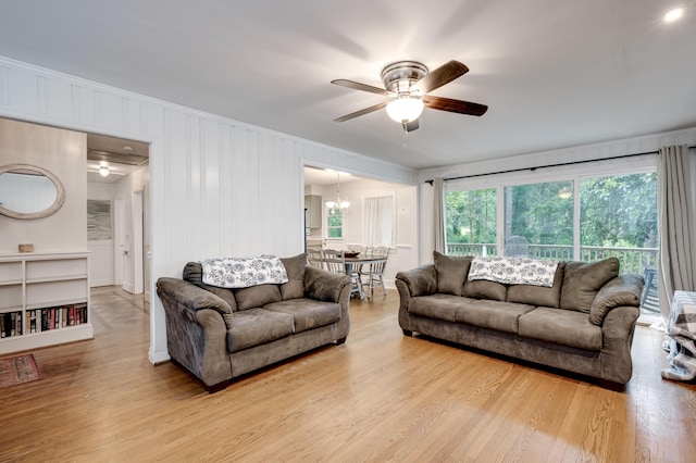living area featuring a ceiling fan, wood finished floors, crown molding, and a chandelier