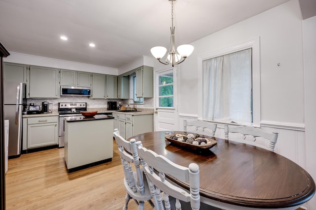 dining space featuring a chandelier, light wood-style floors, and wainscoting