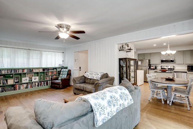living area with crown molding, ceiling fan, a chandelier, and light wood-type flooring