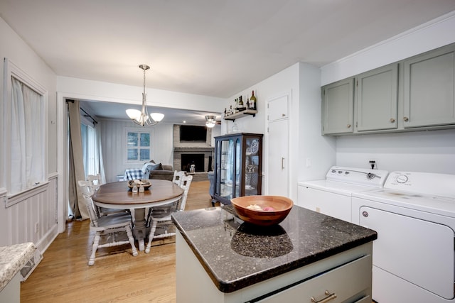 kitchen featuring washing machine and clothes dryer, light wood-style floors, decorative light fixtures, and a brick fireplace