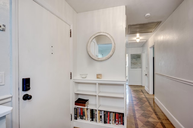 hallway featuring attic access, baseboards, and wood finished floors