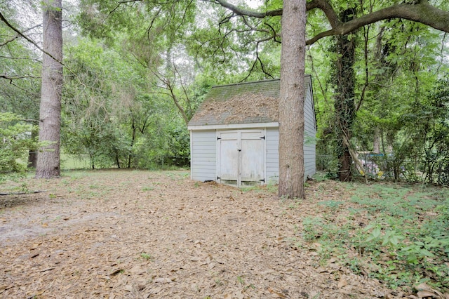view of yard with a shed, an outbuilding, fence, and a wooded view