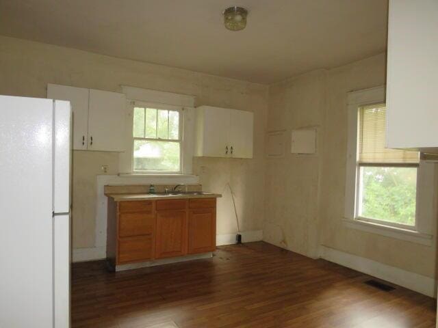 1307 Beman St, Augusta, GA 30904 - kitchen with freestanding refrigerator, wood finished floors, and white cabinets